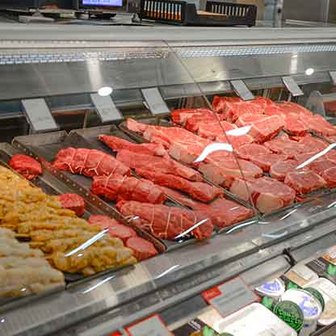 Grocery store butcher case with fresh steaks.