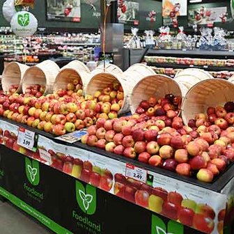 Display of fresh apples in wooden baskets at a Foodland grocery store produce section.