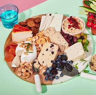 Plant-based charcuterie board with assorted vegan cheeses, nuts, dried fruit, and olives.