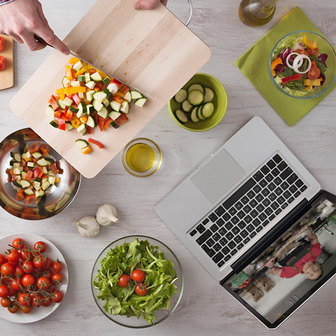 Overhead view of ingredients and a laptop on a white countertop.