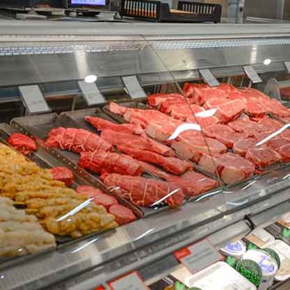 Grocery store butcher case with fresh steaks.