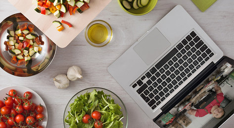 Overhead view of ingredients and a laptop on a white countertop.