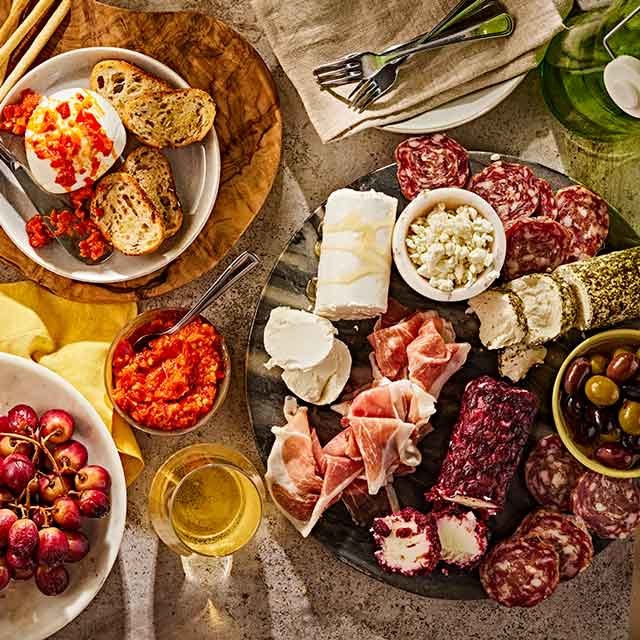 Italian charcuterie board with assorted cured meats, cheeses, olives, bread, and spreads.