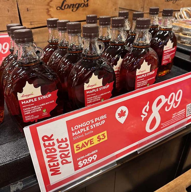 Display of Longo&rsquo;s Pure Maple Syrup bottles with a sign showing member price $8.99 for 500mL, saving $3 from non-member price $9.99.